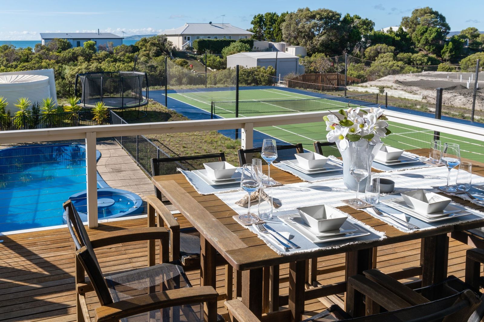 Dining deck overlooking the swimming pool and tennis court