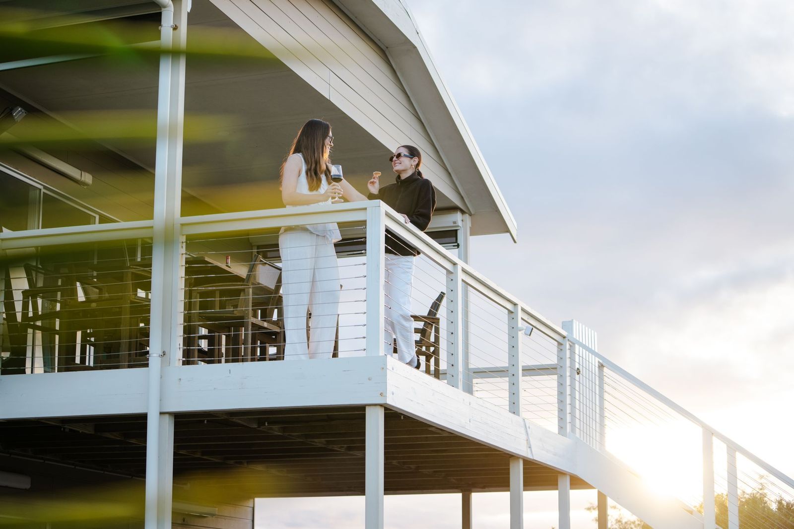 Guests talking on the white timber balcony at Island Beach House