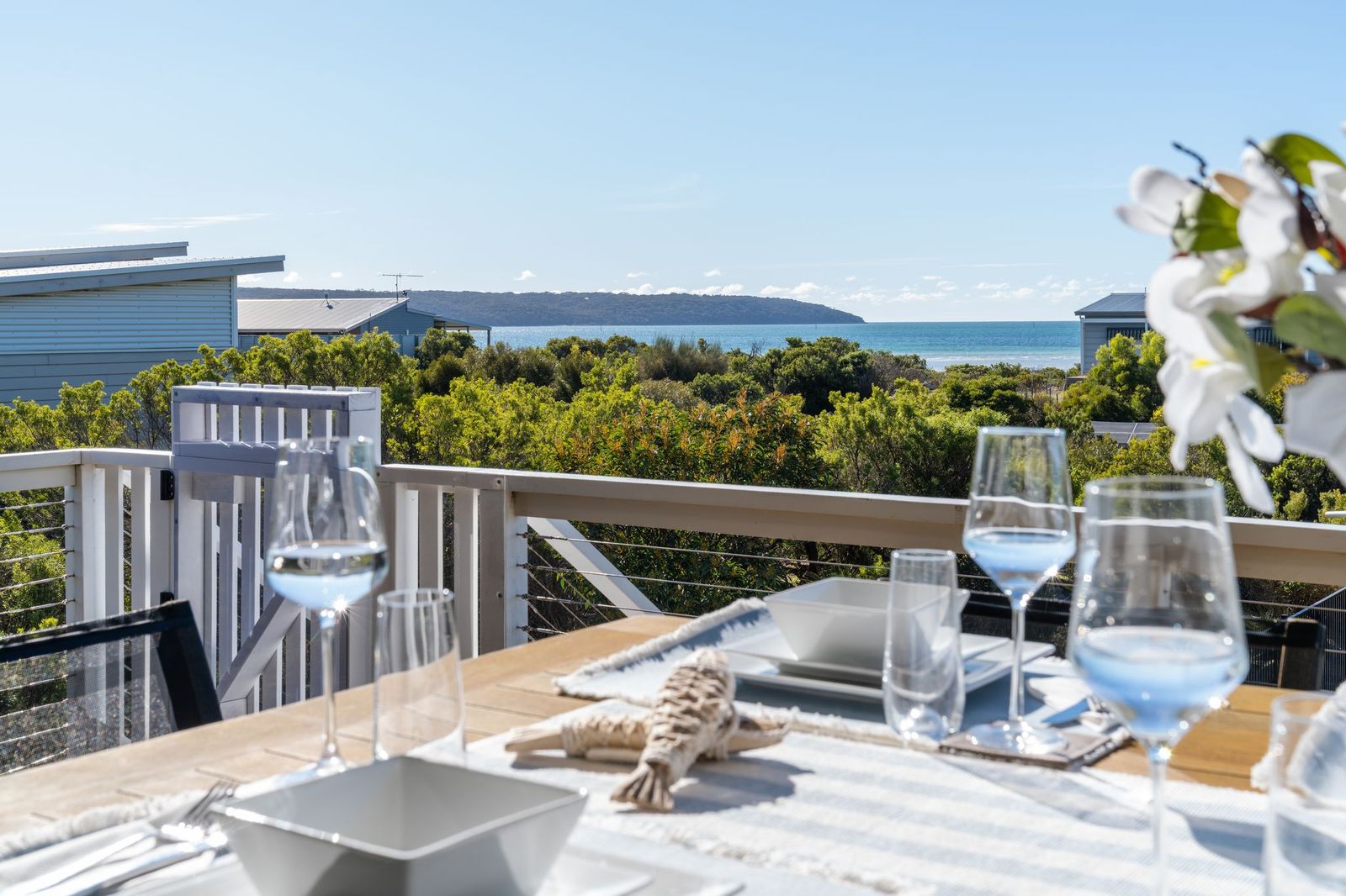 Outdoor dining table set with wine glasses on the deck